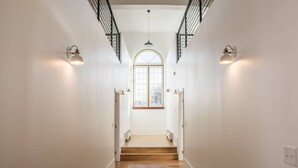 A staircase with white walls, wooden steps, and wall-mounted lighting.