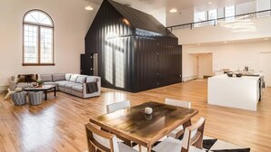 A spacious living area with a large wooden dining table, a cozy sofa, and a modern kitchen with a large island.