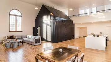 Ein großzügiger Wohnbereich mit einem großen Holzesstisch, einem gemütlichen Sofa und einer modernen Küche mit einer großen Kochinsel.