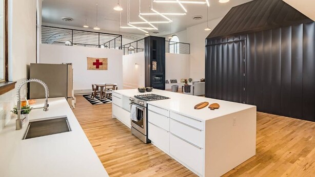 A modern kitchen with a central island, stainless steel appliances, and a wooden floor.