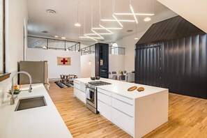 Een moderne keuken met een centraal eiland, roestvrijstalen apparatuur en een houten vloer.