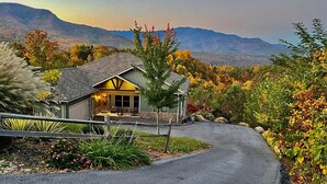 Une maison avec un toit en pente, un porche à l’avant et une vue sur les montagnes.