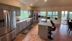 Une cuisine spacieuse, dotée d’appareils électroménagers modernes, de grandes fenêtres et offrant une vue sur l’extérieur.
