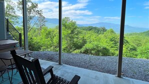 Un balcon avec vue sur une chaîne de montagnes boisées.