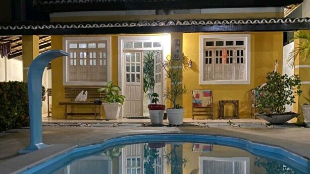 A swimming pool with a reflection of a building with yellow walls and white windows.