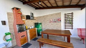 An outdoor kitchen area with a brick oven, a wooden table, and a bench.