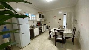 A compact kitchen with white cabinets, a refrigerator, a microwave, and a sink. There is a dining table with four chairs.