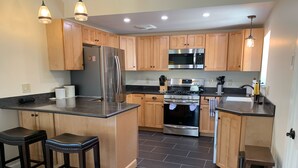 A modern kitchen with wooden cabinets, stainless steel appliances, and black countertops.