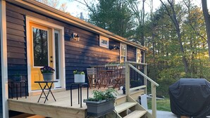 A wooden deck with outdoor furniture, a barbecue grill, and a covered area.
