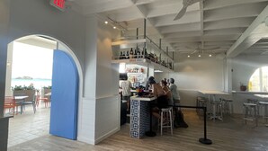 Restaurante com área de bar, mesas e vista para o mar.