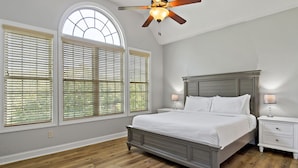 A bedroom with a bed, nightstands, a ceiling fan, and large windows with blinds. - Shumont Lake Lakefront, Resort Access - All Decked Out by Carolina Properties (Lake Lure)