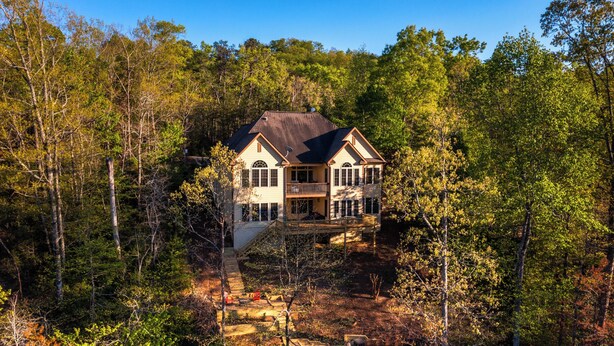 A large, two-story house surrounded by dense forest. - Shumont Lake Lakefront, Resort Access - All Decked Out by Carolina Properties (Lake Lure)