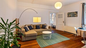 Un salon avec un canapé, une lampe, une table ronde et une plante.