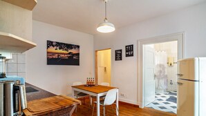 Une cuisine avec une table en bois, des chaises, une machine à café et un réfrigérateur.