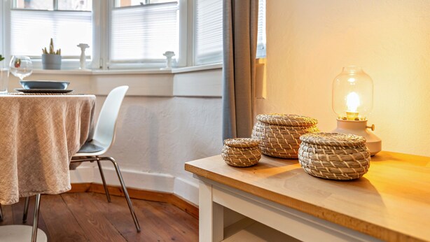 Un coin repas avec une table, des chaises et des paniers en osier posés sur une table en bois.
