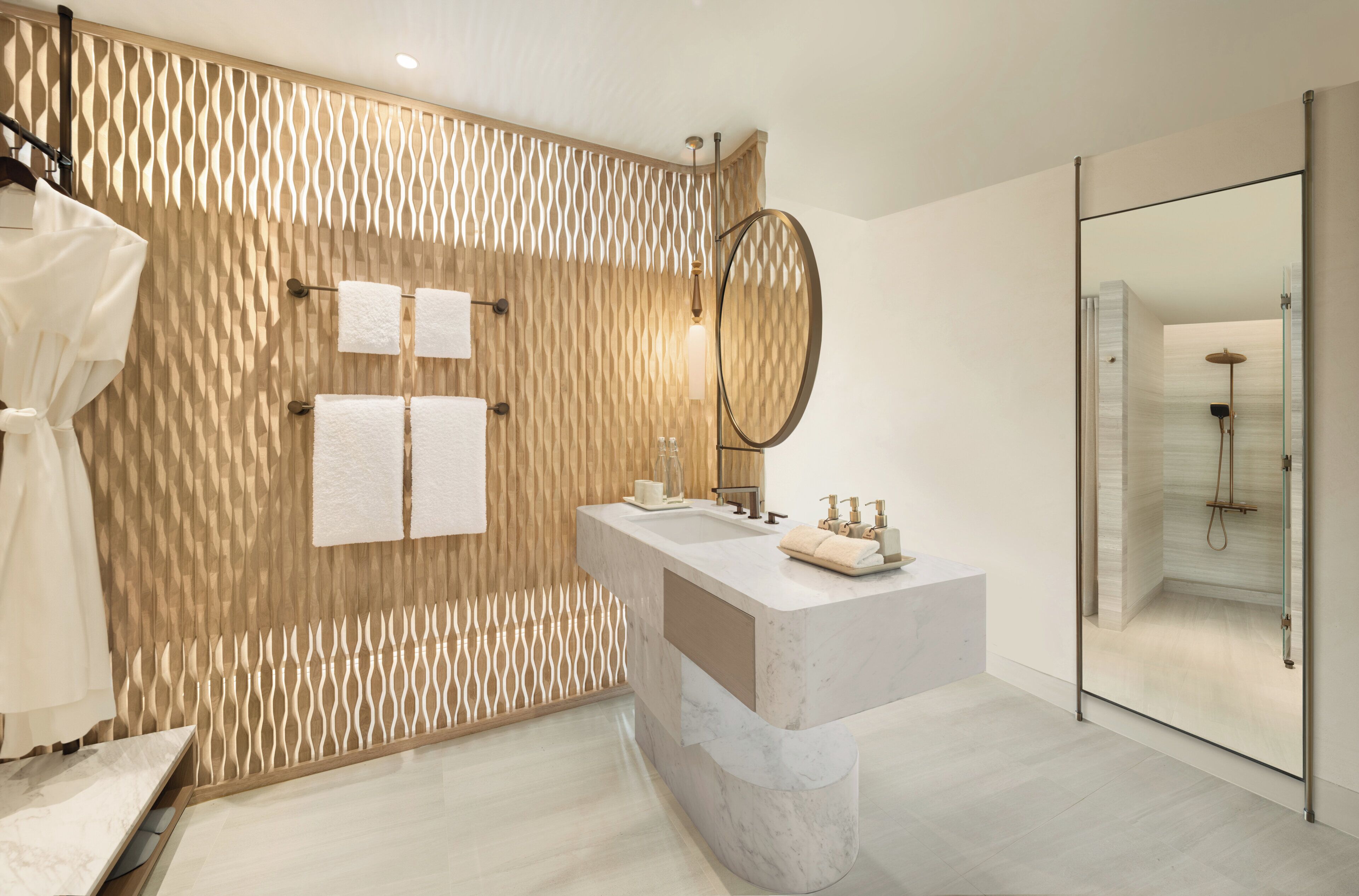 Un baño moderno con pared de textura de madera, un espejo grande, lavamanos de mármol y ducha con mampara de vidrio.