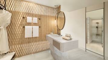 Un baño moderno con pared de textura de madera, un espejo grande, lavamanos de mármol y ducha con mampara de vidrio.