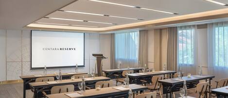 A conference room with a large screen displaying 'CENTARA RESERVE,' tables with water bottles, and a podium.
