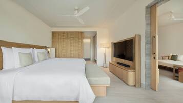 Habitación de hotel con una cama grande, un televisor de pantalla plana en la pared, una mesita de noche y un ventilador de techo.