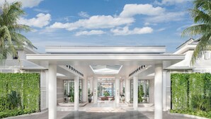 A modern hotel entrance with a covered walkway, large columns, and a central fountain. - Centara Reserve Samui (Koh Samui)