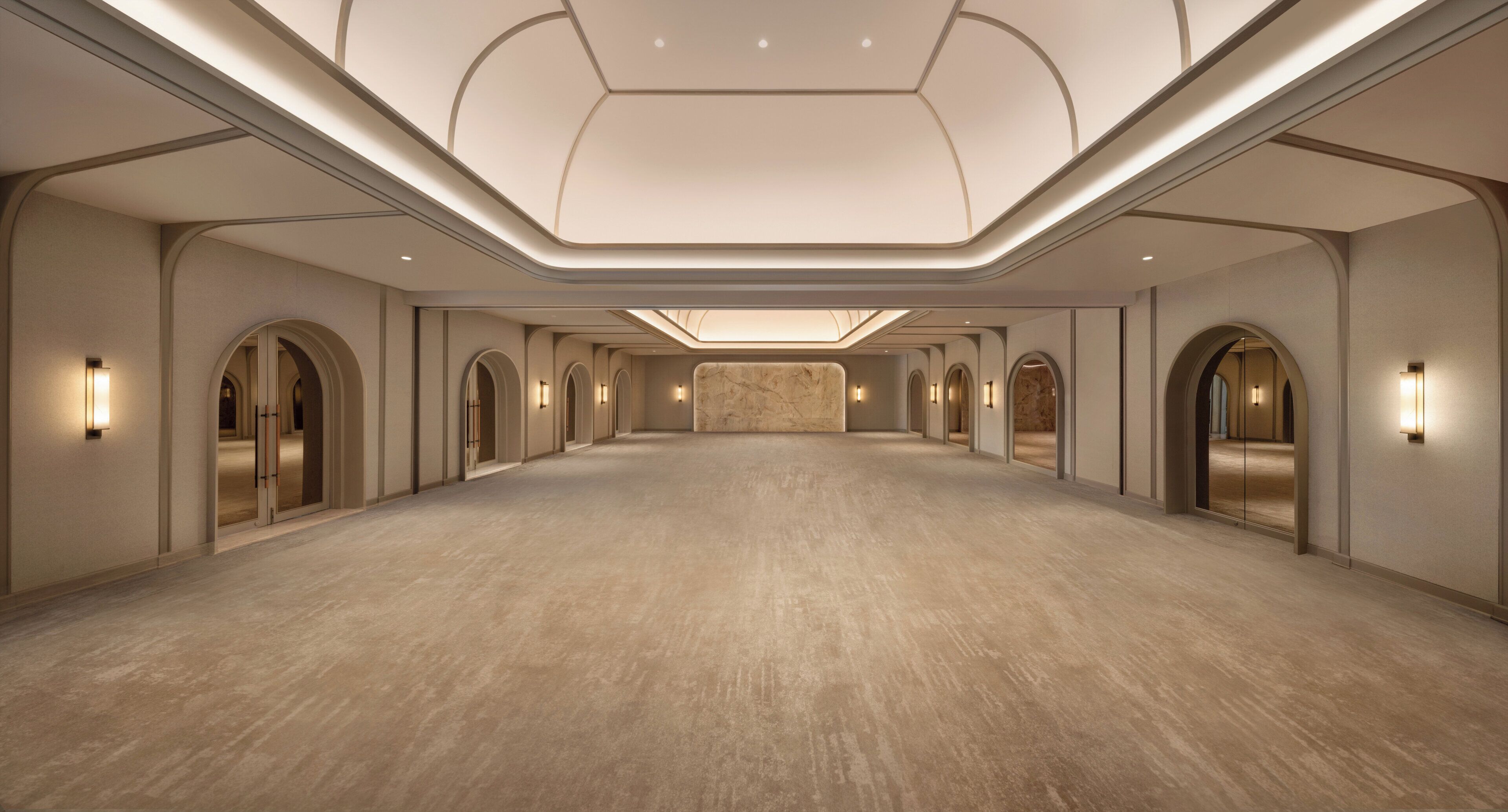 A spacious, well-lit hotel lobby with a high ceiling and arched doorways.