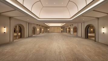 A spacious, well-lit hotel lobby with a high ceiling and arched doorways.
