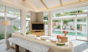 A modern living room with a TV, sofa, and pool view. - Centara Reserve Samui (Koh Samui)