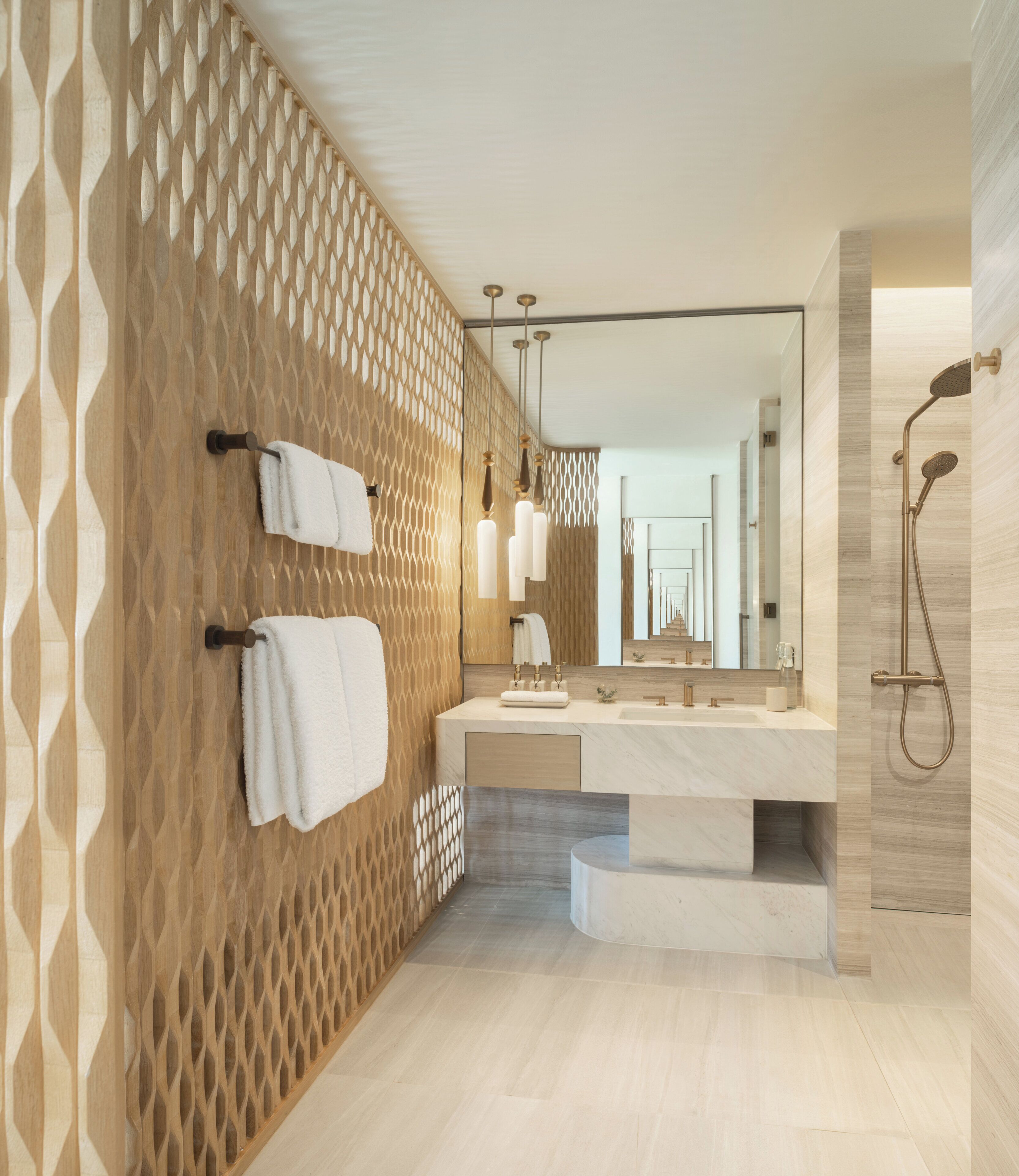 Une salle de bain moderne avec un mur en treillis de bois, un grand miroir, un lavabo doté d’un plan de travail en marbre et un espace douche.
