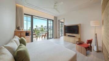 A modern hotel room with a large bed, a TV, a balcony with a view of palm trees, and a dining area.