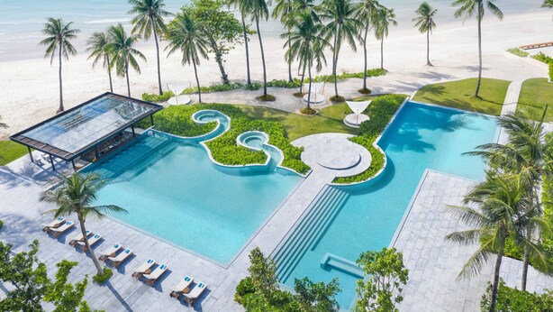 A resort pool with a clear view of the ocean, surrounded by palm trees and a sandy beach. - Centara Reserve Samui (Koh Samui)