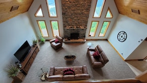 Un salón amplio con chimenea de piedra, varias ventanas y una zona de estar acogedora.