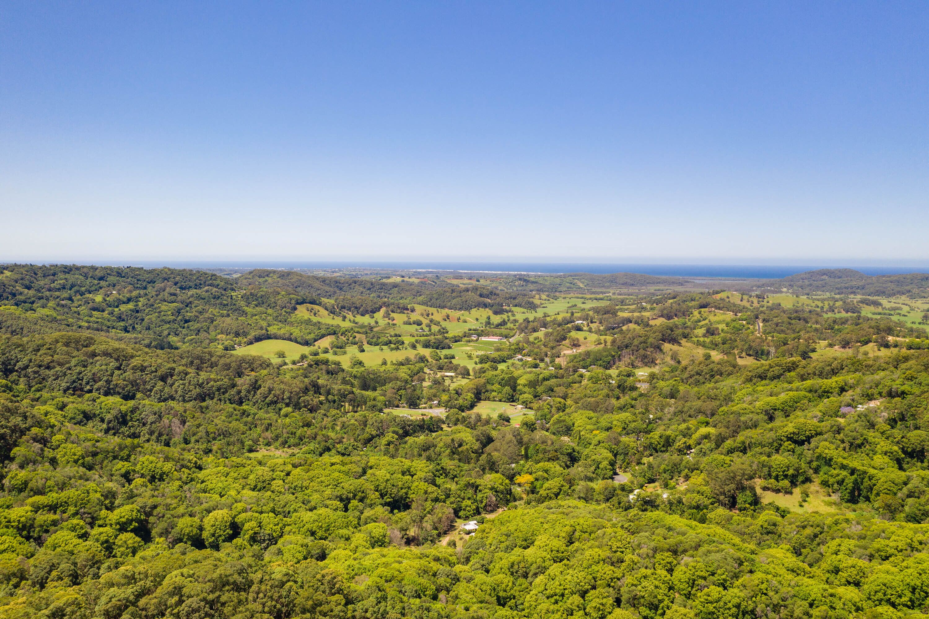 Ein weites Panorama über eine üppige, grüne Landschaft mit sanften Hügeln und verstreuten Gebäuden.