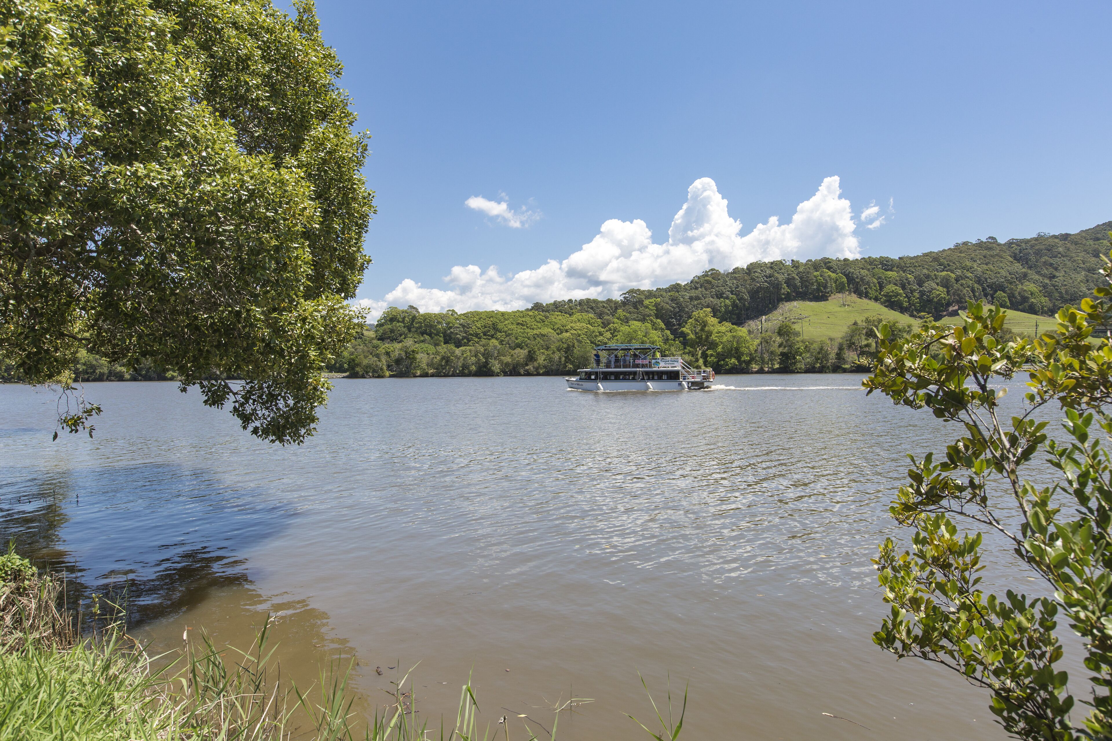 Un barco sobre un lago tranquilo rodeado de exuberante vegetación y colinas.
