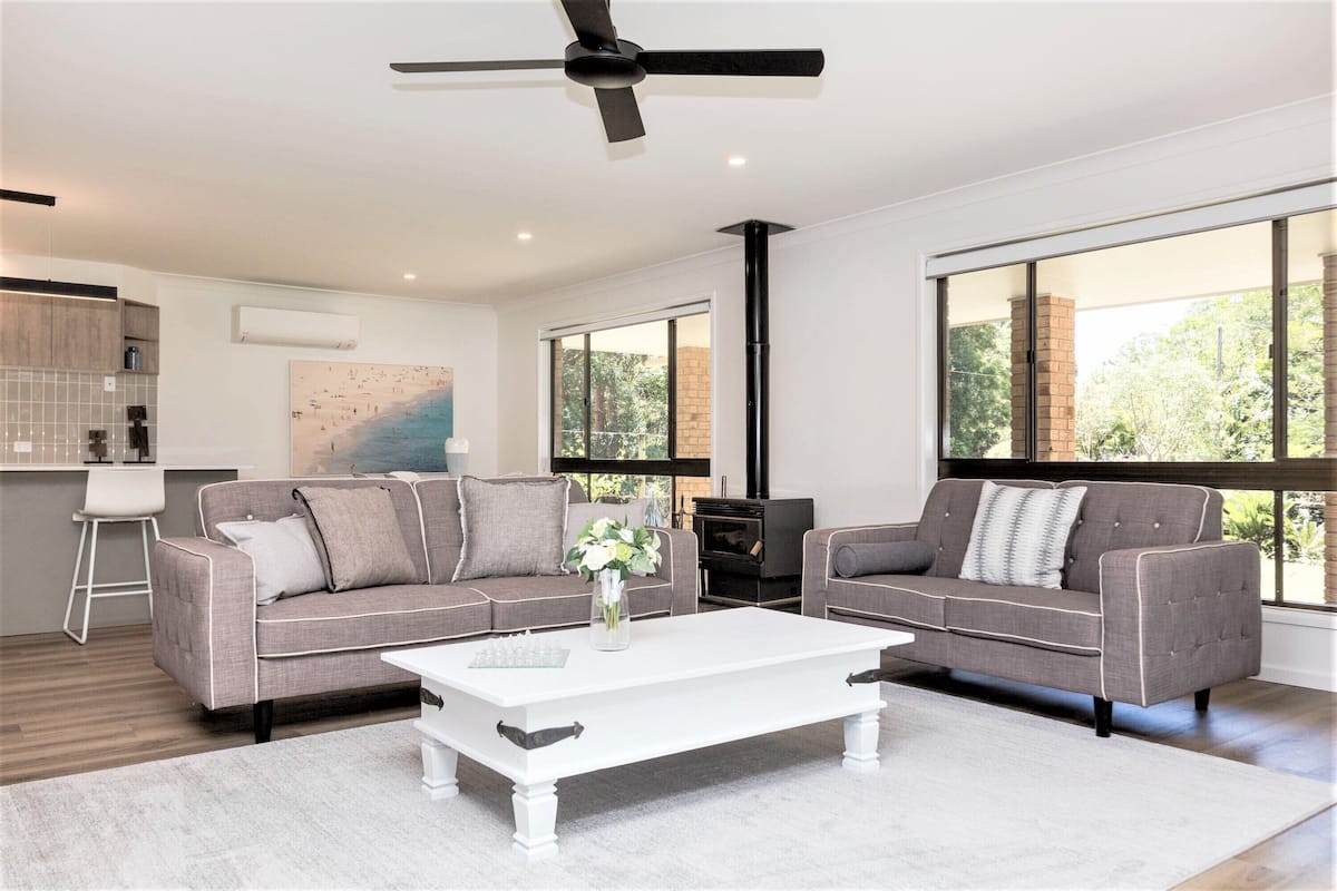 A modern living room with two grey sofas, a white coffee table, and a ceiling fan.