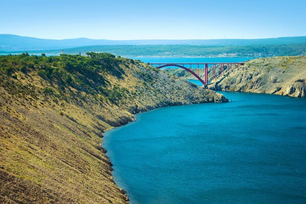 A red bridge over a river with a hilly landscape in the background. - Sea View Apt Silver near Zadar, Jasenice, Croatia (Jasenice)