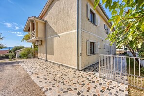 A two-story building with a balcony, a tiled patio, and a metal gate.
