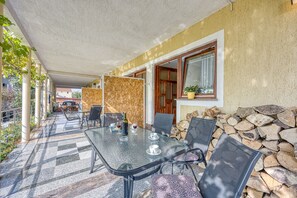 An outdoor patio with a glass table, chairs, and a stack of firewood.