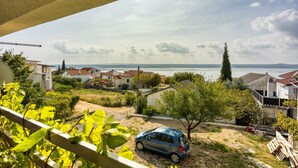 A residential area with houses, a parked car, and a view of the sea. - Turquoise Apartment Sea View, Jasenice, Croatia (Jasenice)