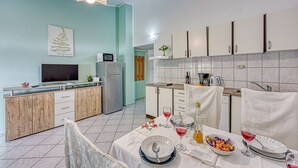 A modern kitchen with white cabinets, a dining table set with plates, glasses, and a bowl of snacks. - Turquoise Apartment Sea View, Jasenice, Croatia (Jasenice)
