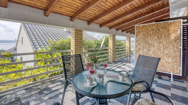 A covered outdoor seating area with a round glass table, two chairs, and a view of the sea. - Turquoise Apartment Sea View, Jasenice, Croatia (Jasenice)