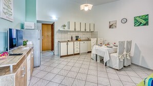 A modern kitchen with a dining area, featuring a refrigerator, microwave, cabinets, and a dining table set for two. - Turquoise Apartment Sea View, Jasenice, Croatia (Jasenice)