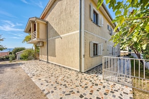A two-story house with a tiled patio, a balcony, and a metal gate. - Orange Apartment Sea View, Jasenice, Croatia (Jasenice)