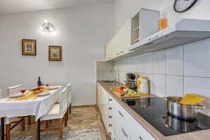 Eine moderne Küche mit Essbereich, ausgestattet mit einem Herd, Kochtöpfen und einem Esstisch für vier Personen.