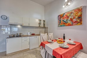 A modern kitchen with white cabinets, a dishwasher, and a dining area with a red tablecloth.