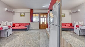 Een kamer met twee bedden, een koelkast en een raam met gordijnen.