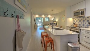 Une cuisine moderne dotée d’un îlot central, de tabourets en bois, d’un four à micro-ondes et d’un évier.