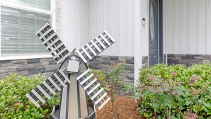 Un moulin à vent dans un jardin, avec une maison en arrière-plan.