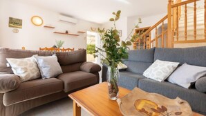Una sala de estar con dos sofás, una mesa de centro de madera y un jarrón con plantas.
