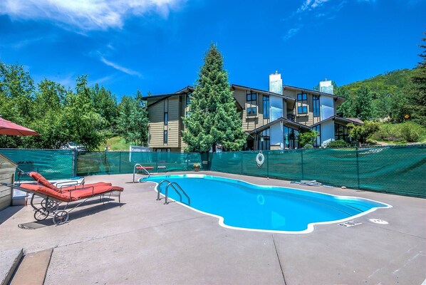 A swimming pool with a red lounge chair and a metal ladder. - Blocks to the Slopes | Fireplace & Winter Shuttle (Steamboat Springs)