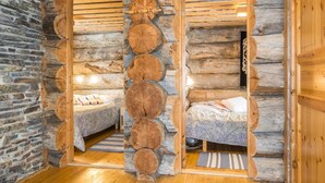 Een blokhut inrichting met twee slaapkamers, elk met een bed en een klein raam.